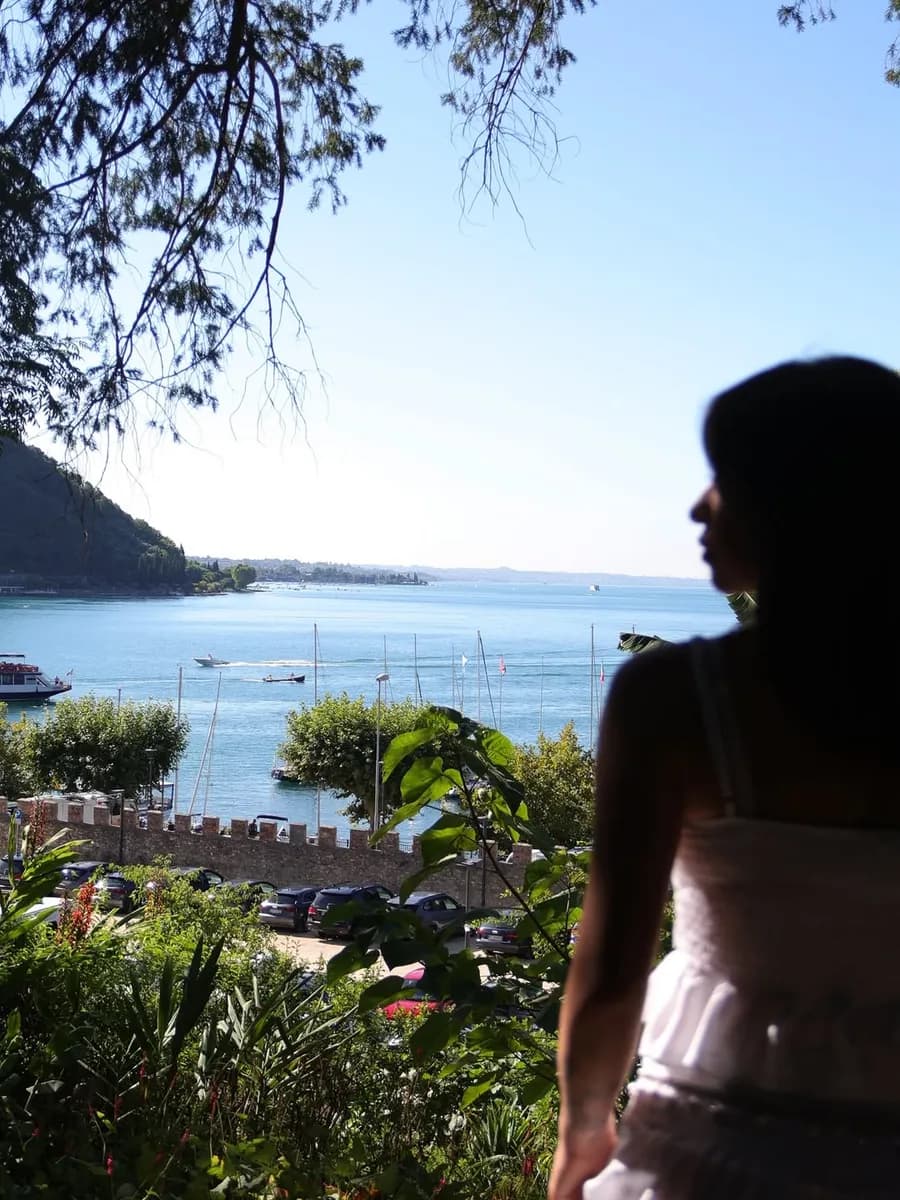 Una visitatrice osserva il lago di Garda tra le canne del parco
